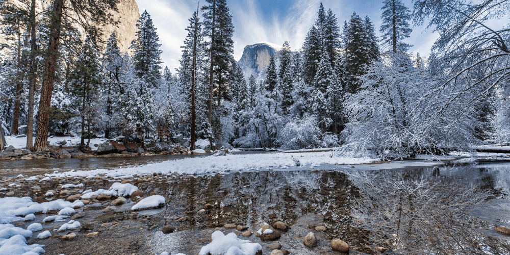 Merced river in Yosemite surrounded by snow covered trees and rocks