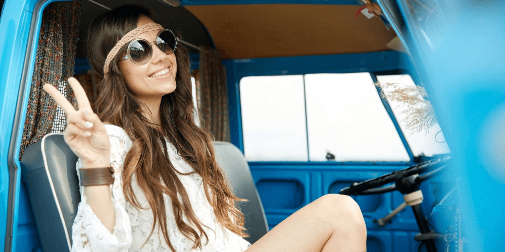 a brunette girl dressed like hippie showing peace sign in the back of blue track