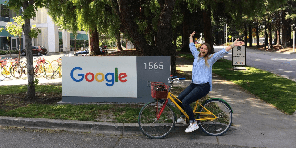 blonde girl posing with her bike in front of google sign