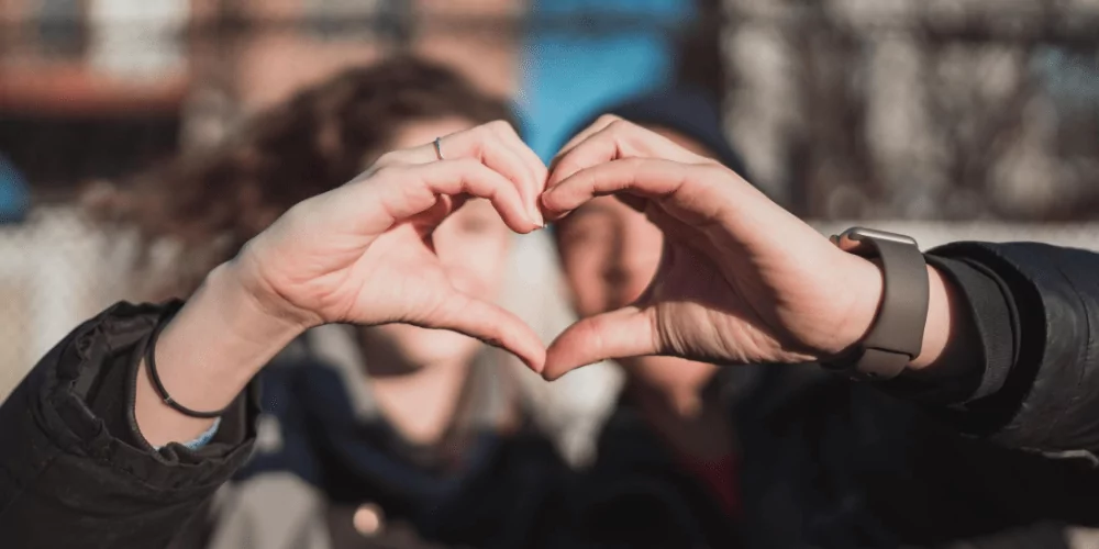 two people making a heart shape with their hands