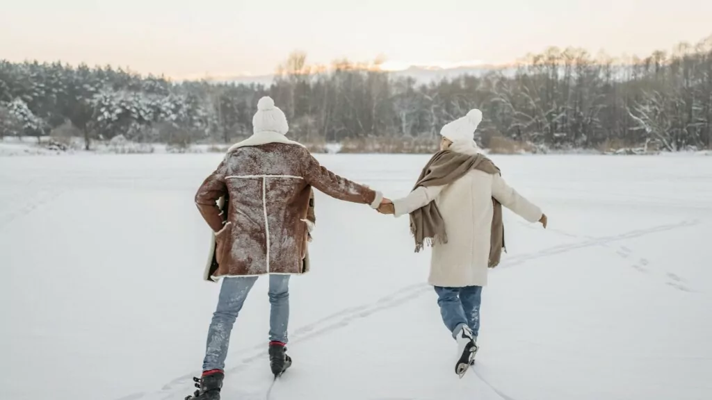 a couple with white beanies skating hand in hand