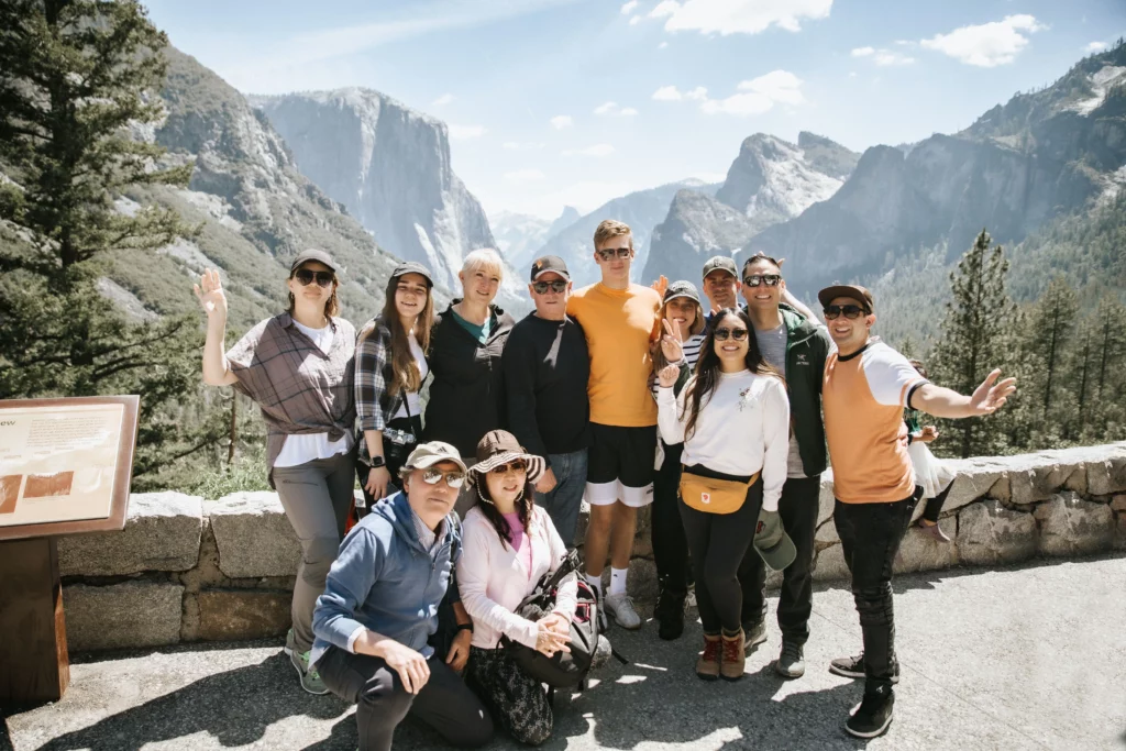 a group of smiling people standing at the tunnel view lookout in yosemite
