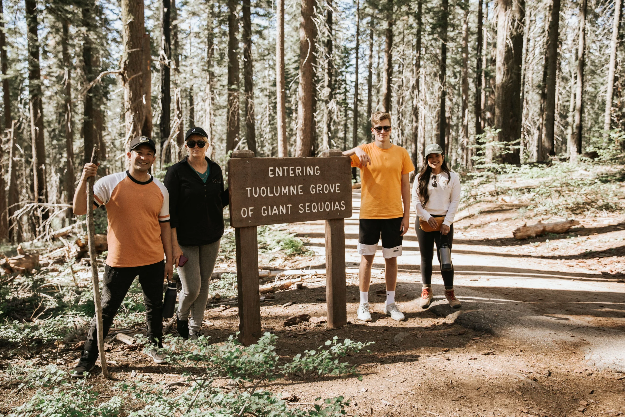 people standing next to the sign that says entering tuolumne grove of giant sequoias