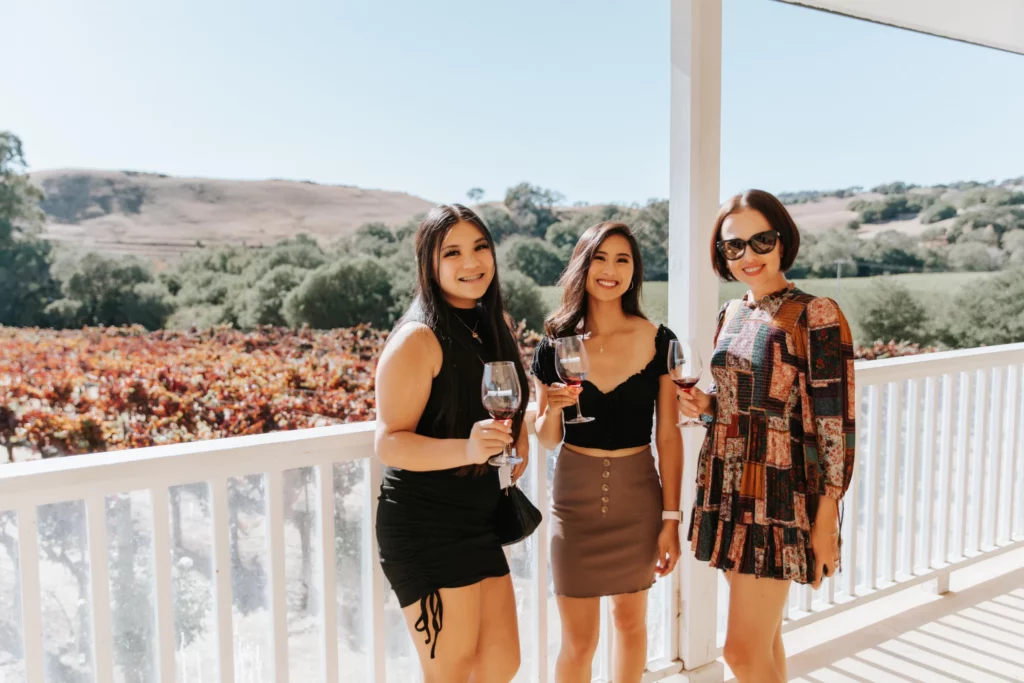 three girl posing in front od vineyards