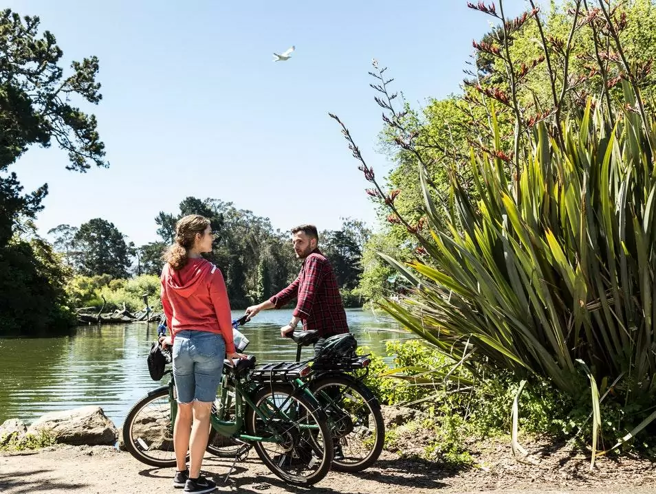 couple standing with bikes near lake in the golden gate park