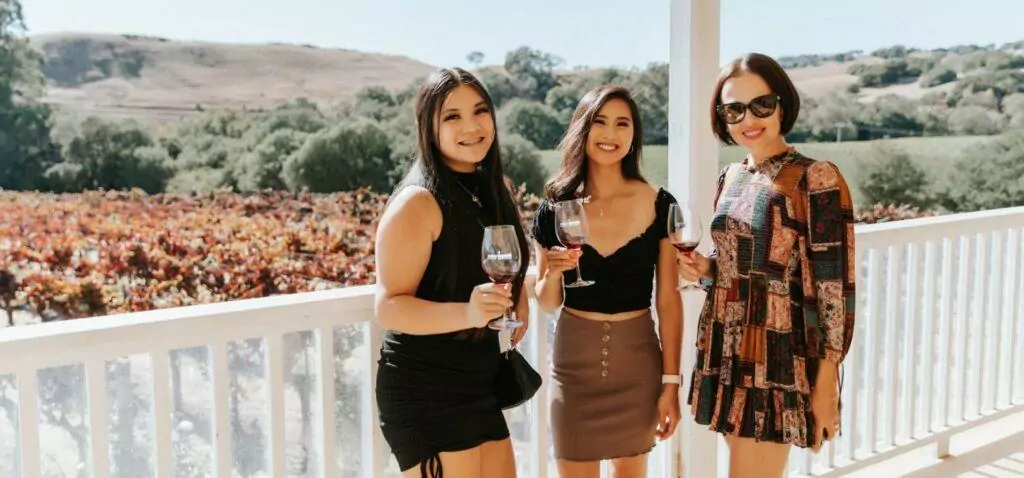 three girls standing with glasses of wine on the porch of Ru Vango winery