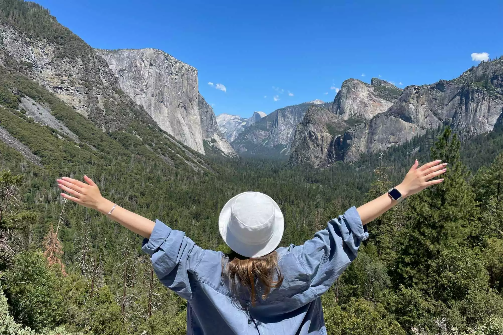 girl with her hands in the air looking at valley from Tunnel View overlook in Yosemite