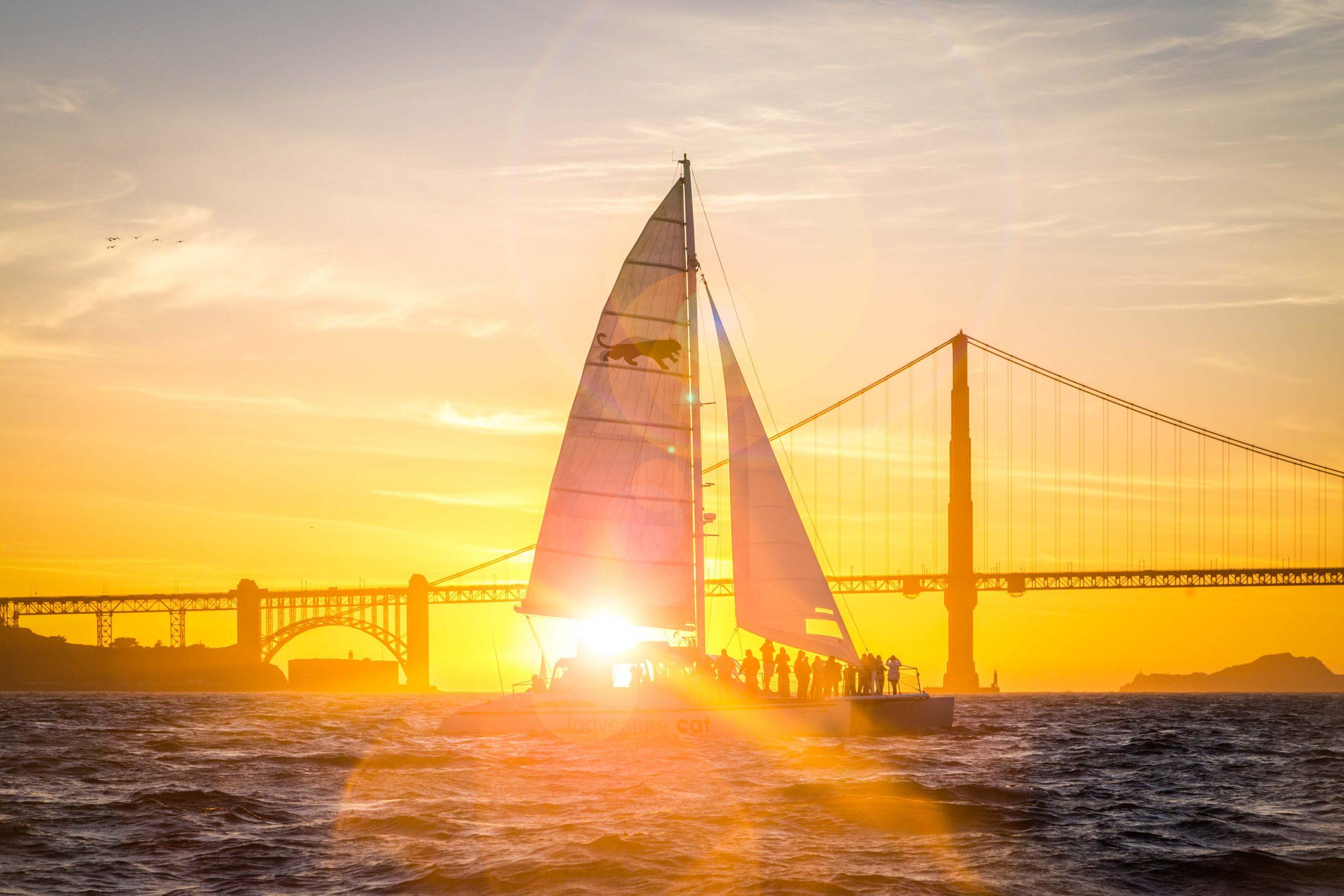 catamaran in front of golden gate bridge during sunset