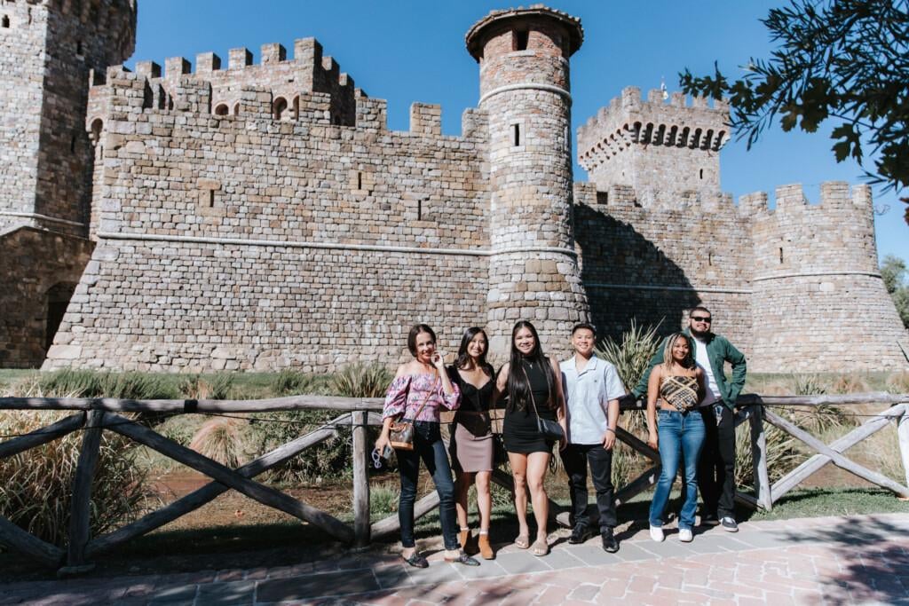 people posing in front of castello di amorosa winery castle