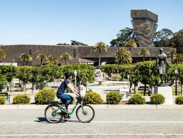 man riding a bike in front of a museum