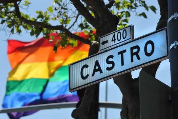 rainbow flag in front of the castro street sign