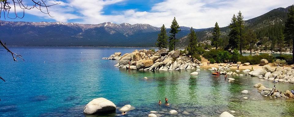 clear lake around pine trees and mountains