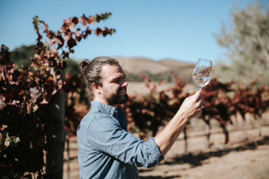 man looking at a glass of wine in the vineyard