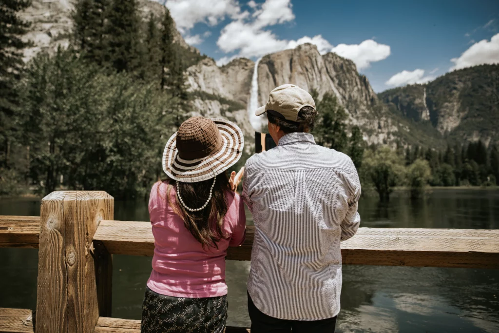 a woman in hat and man in grey shirt looking at yosemite falls from swinging bridge