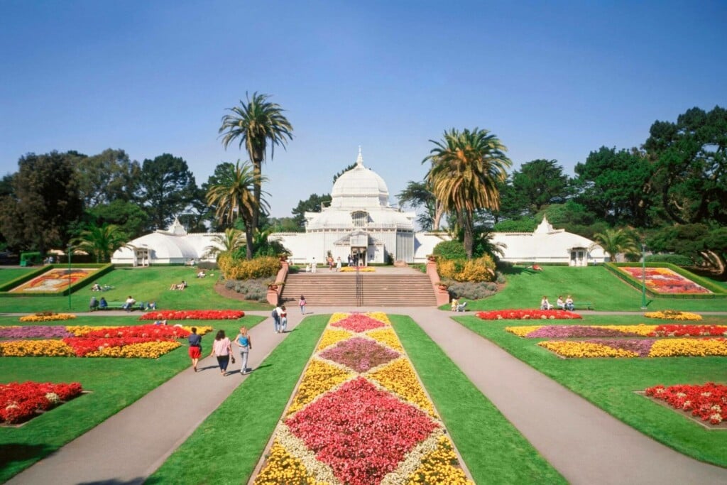 a group of people strolling through the conservatory of flowers park 
