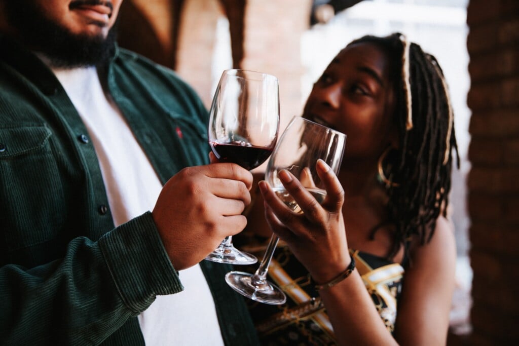 two people toasting a glass of red wine