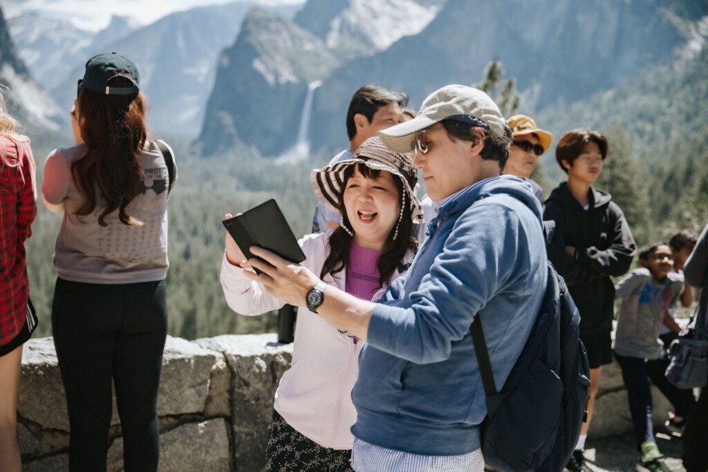 a woman in a hat and man in blue shirt looking at photos on their phone at the tunnel view