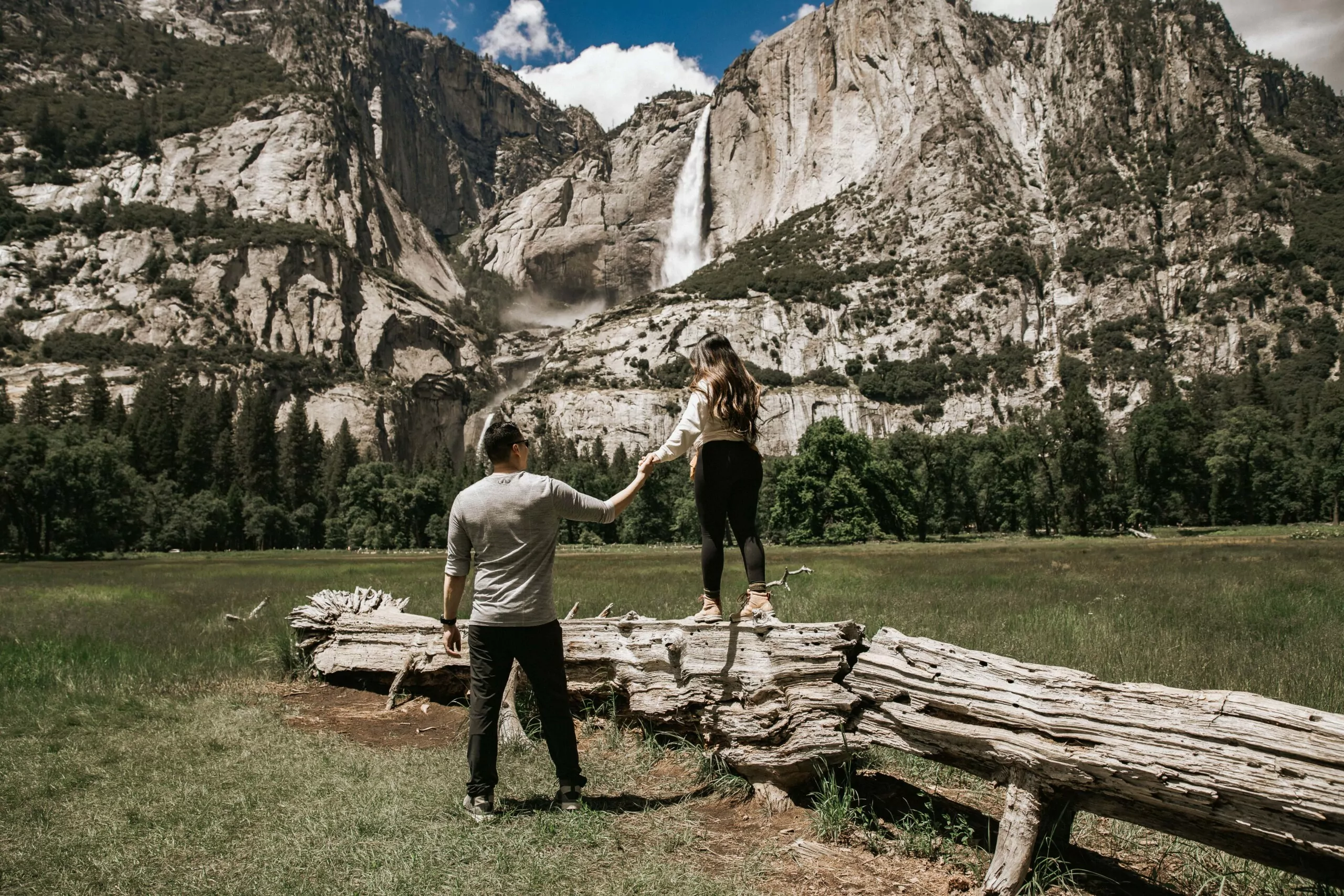 a couple holding hands in front of yosemite falls