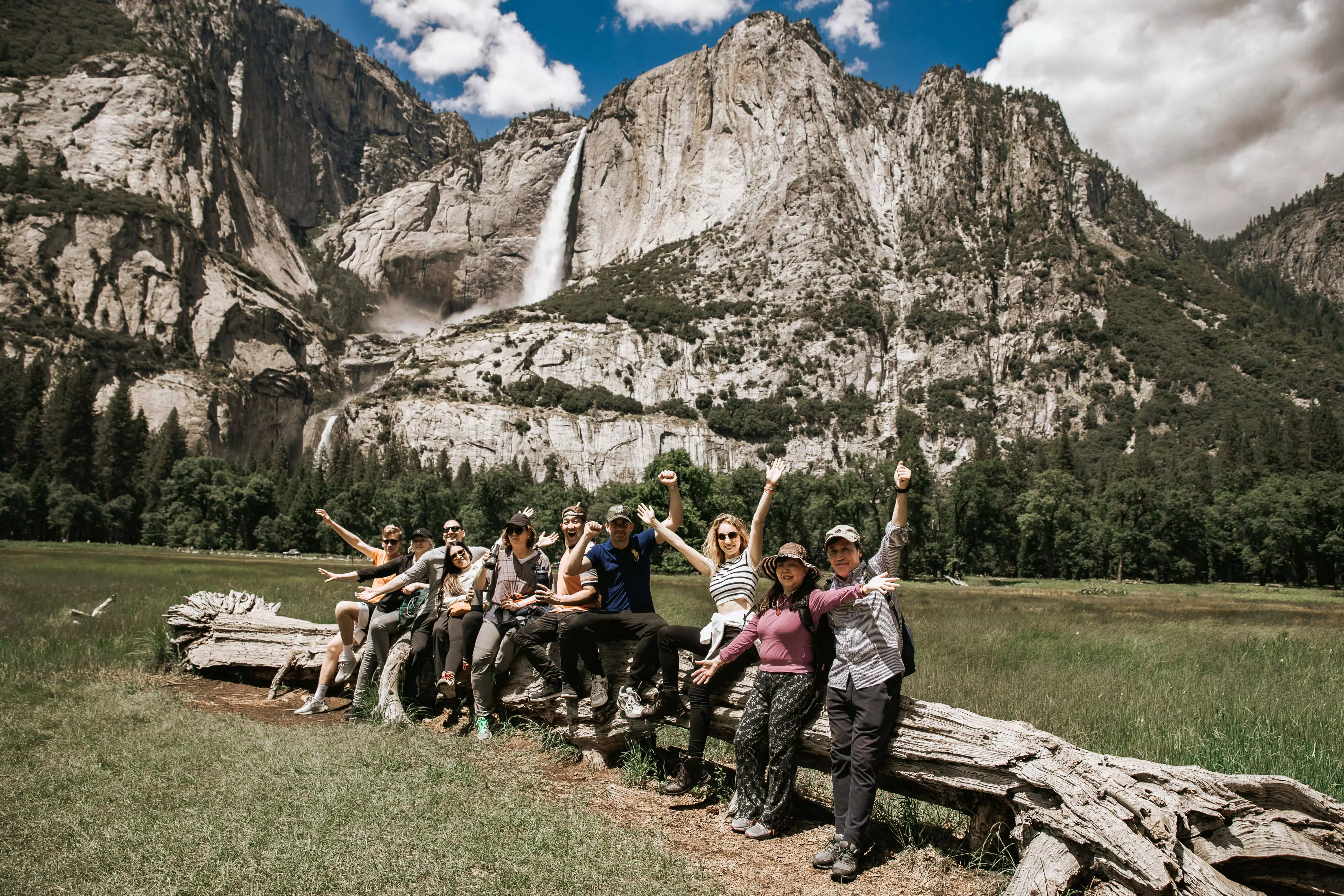 a group of smiling people standing in front of yosemite falls