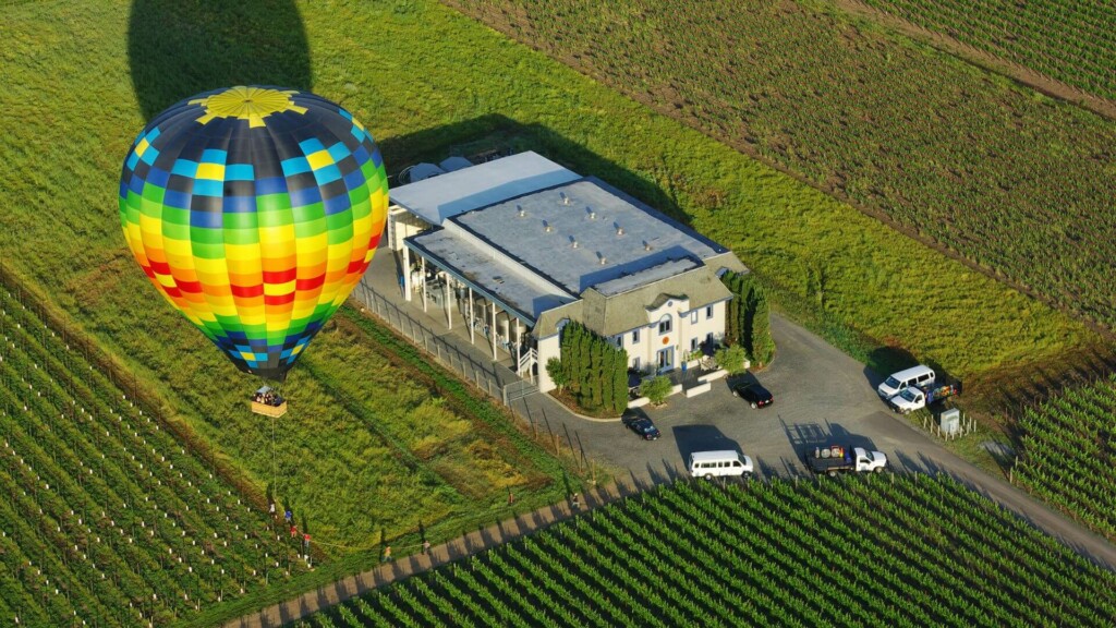 a bird's view of a winery establishment with a hot air balloon beside 