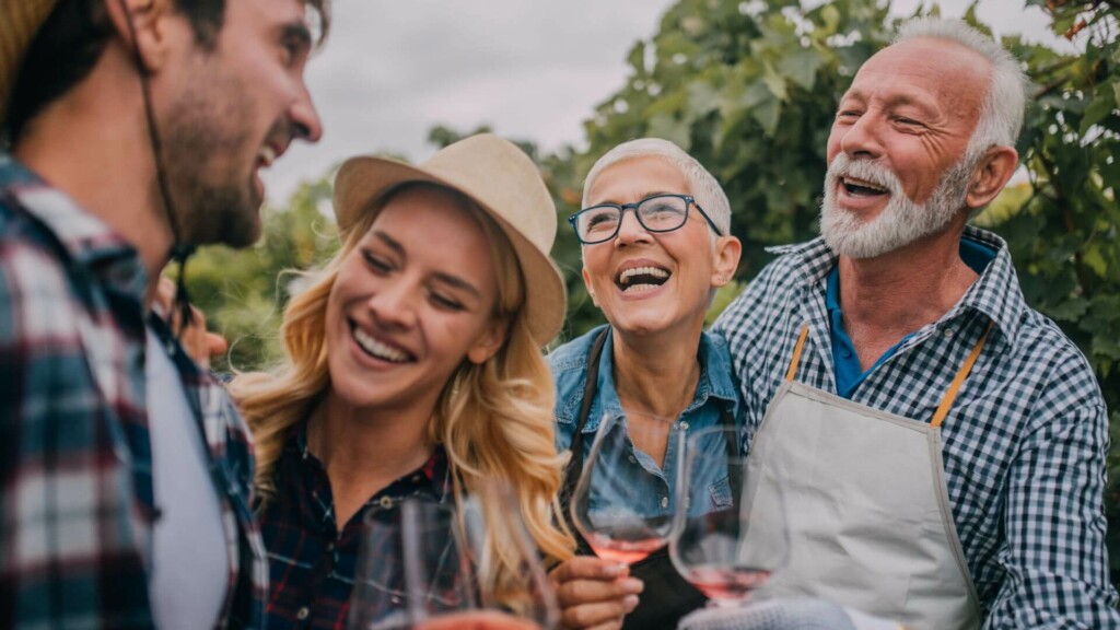 group of four people laughing and enjoying wine at the vineyard 