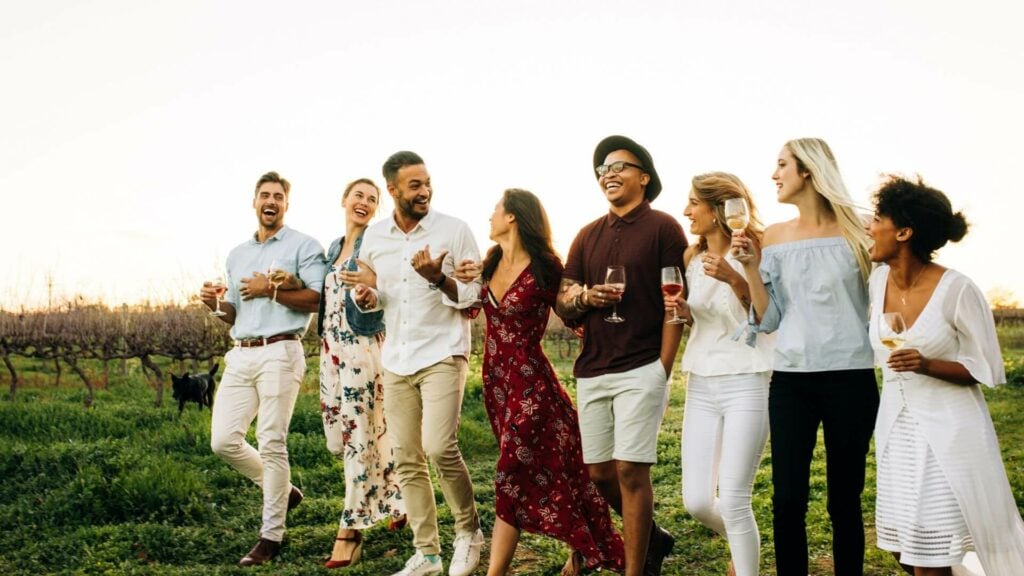 a group of people smiling with glasses of wine in hand