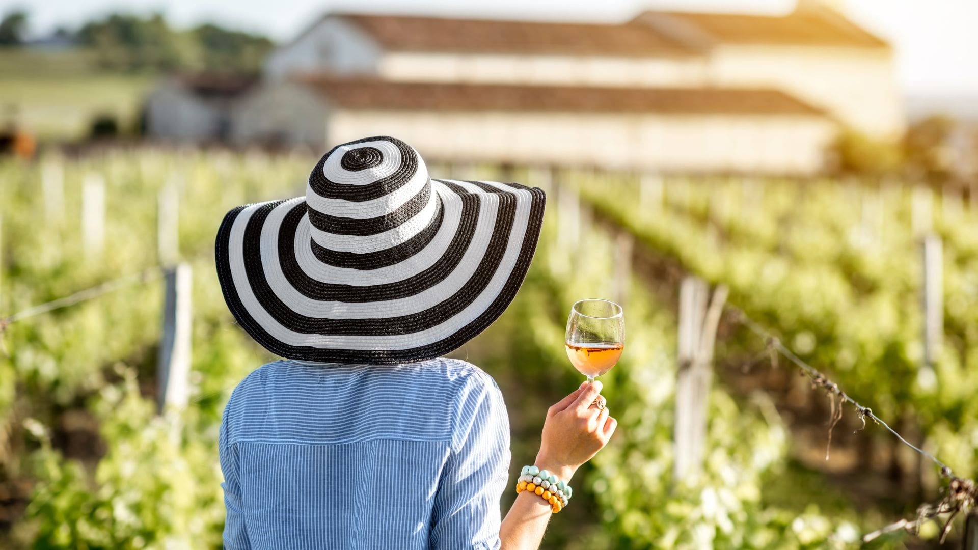 a woman wearing a striped hat with a glass of wine in hand