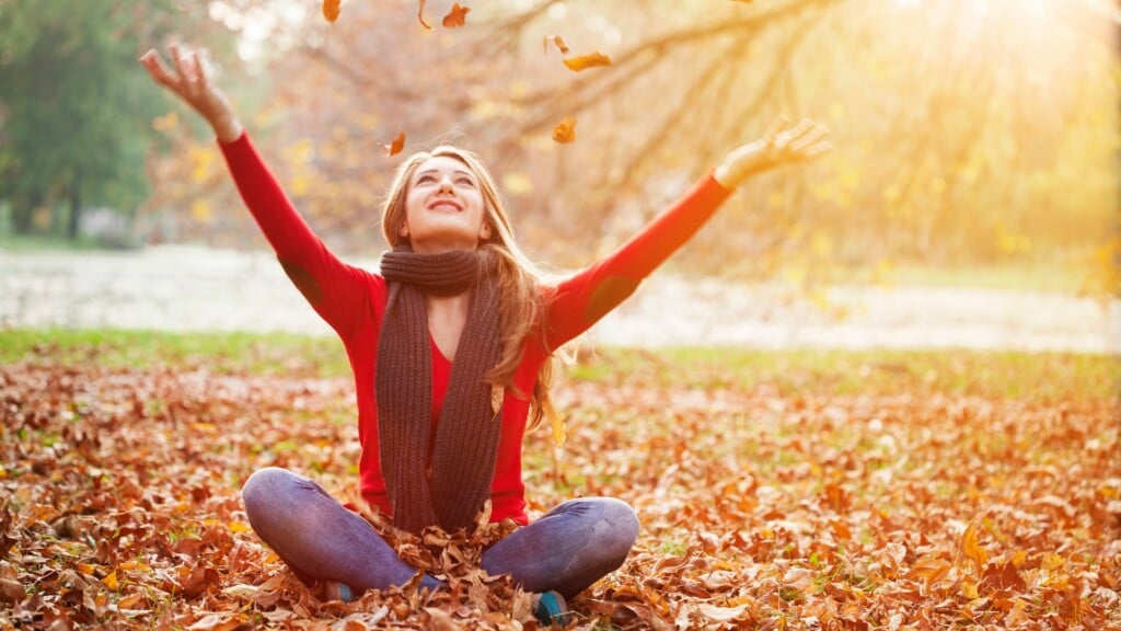 a woman in red sweater sitting on fallen leaves during the fall in San Francisco