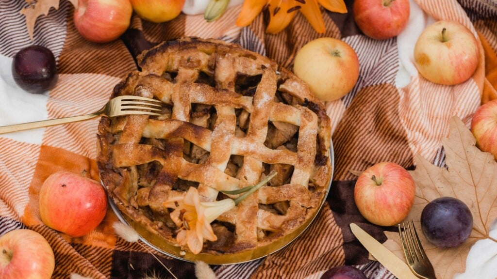 apple pie served in a plate surrounded by ripe apples 