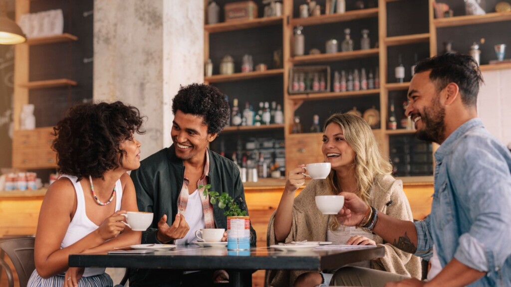 a group of people sitting around at a table with coffee cups in hand 