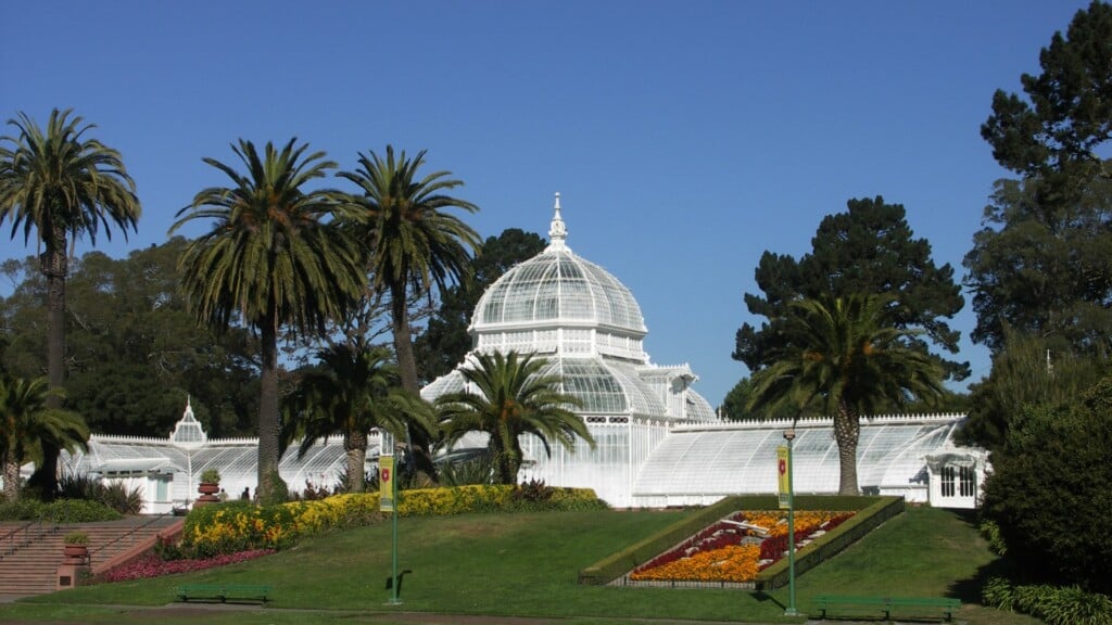 a photo of a tall white structure surrounded by green grass and bloomed flowers 