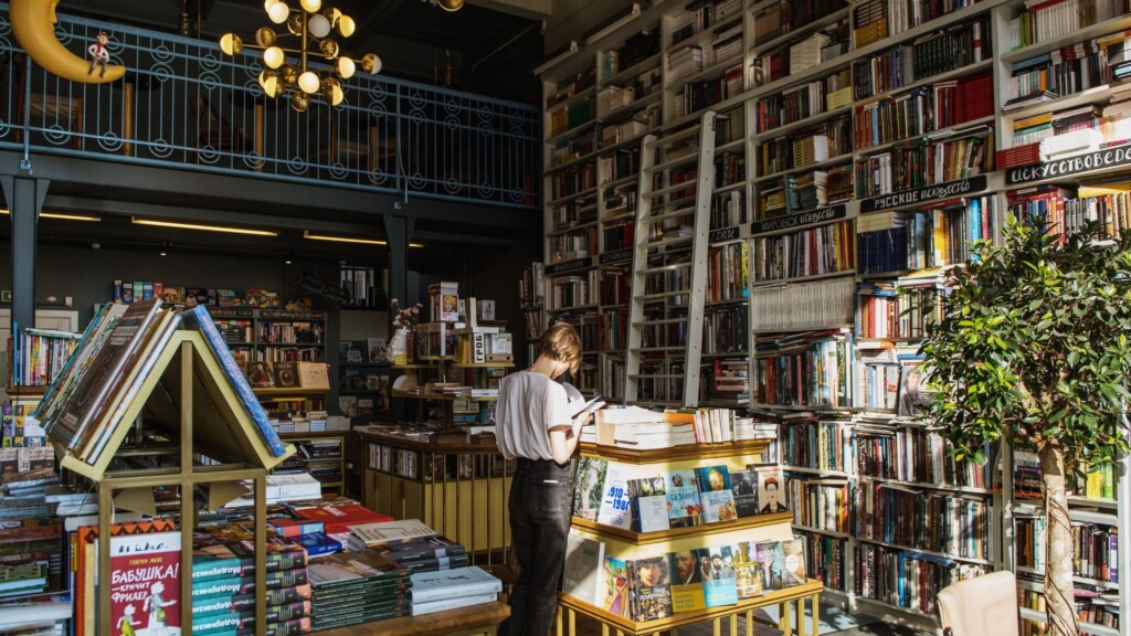 a woman standing in a middle of a store surrounded by books indoors on a rainy day