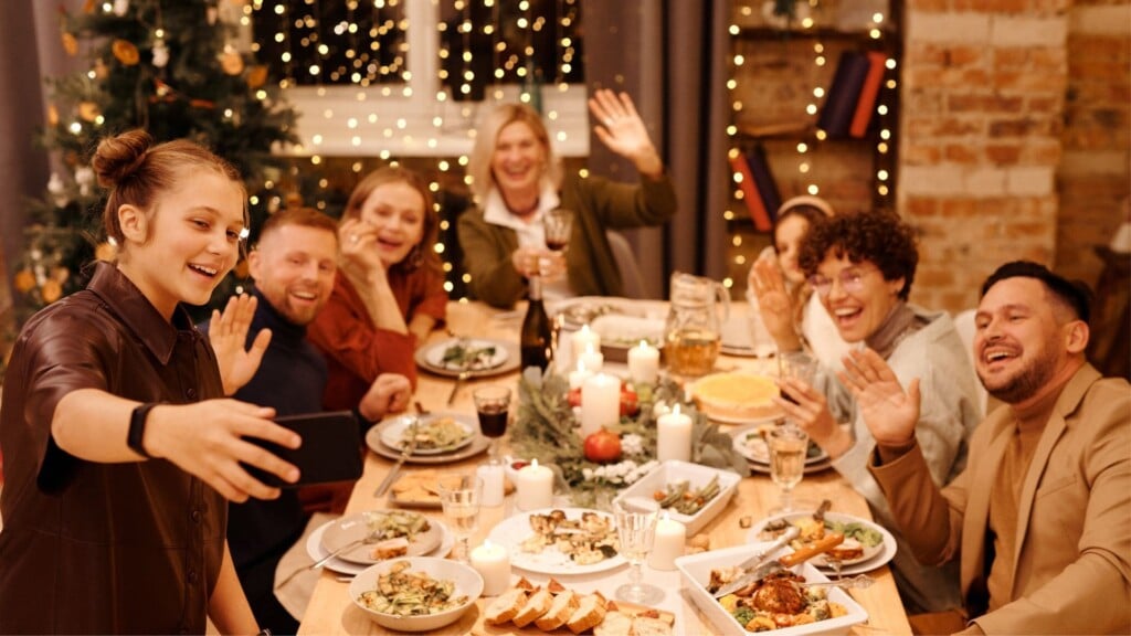 group of people sitting down at a christmas dinner smiling to take a photo 