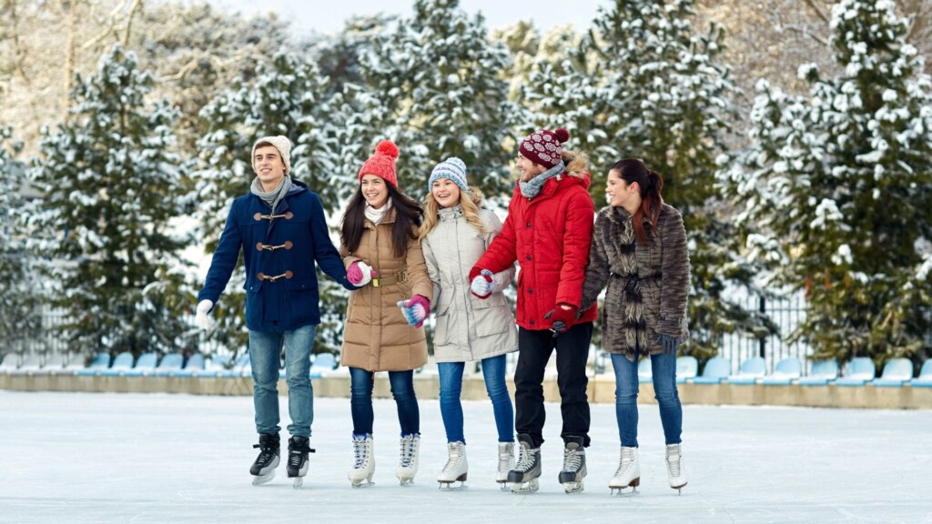 a group of friends skating in an ice rink with pine trees as background 