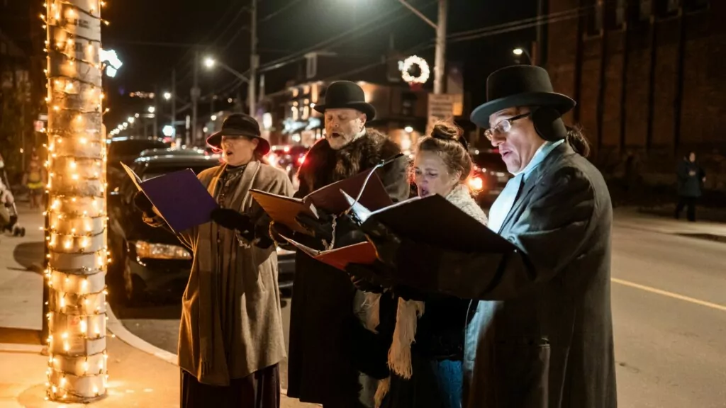 a group of christmas carolers holding a book while singing