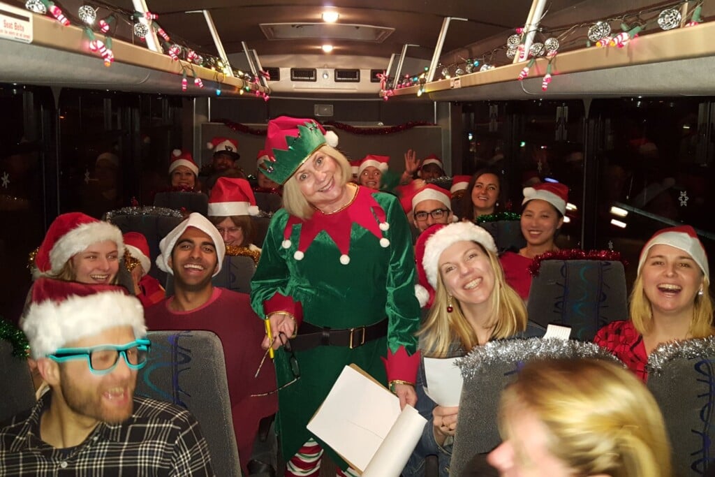 a woman in a green Christmas costumes smiling for a photo