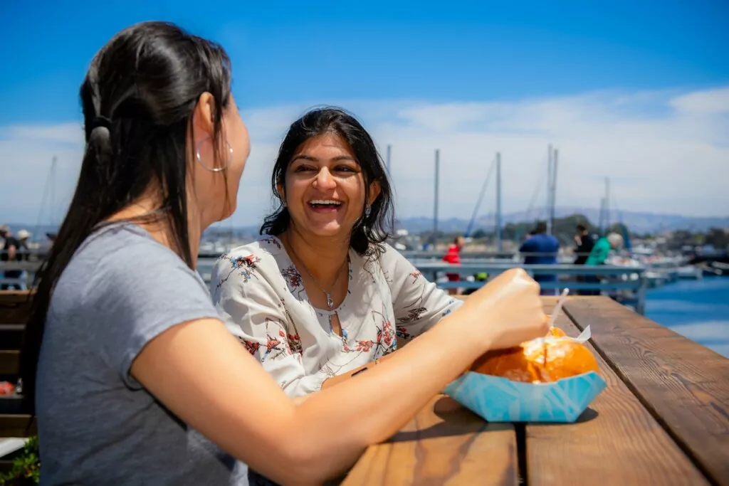 two women eating snack by monterey bay 