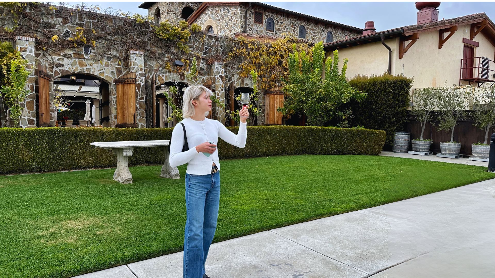 An individual tasting wine while standing in front of a winery