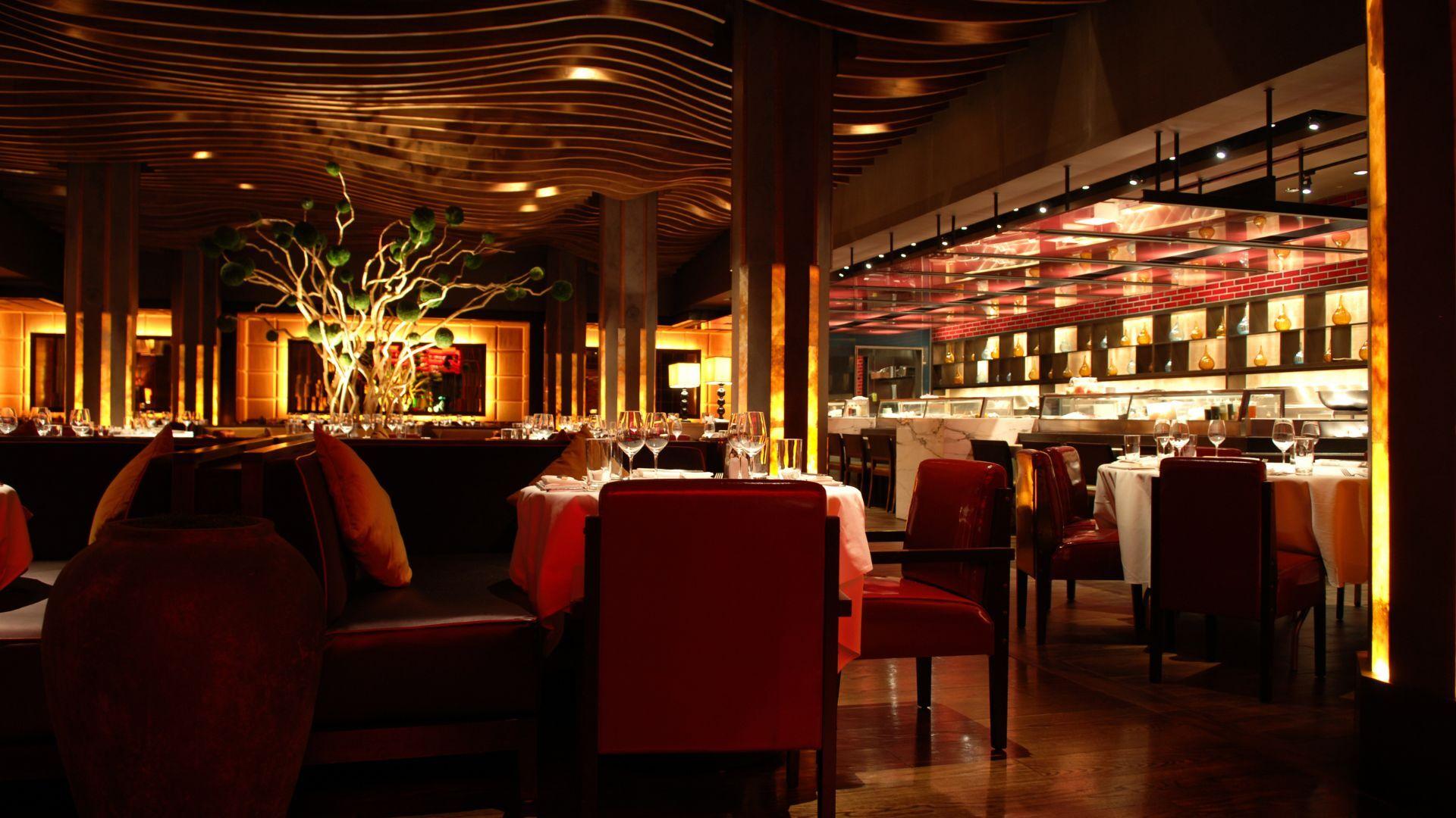 A luxurious restaurant with warm lighting, elegant décor, and a modern open kitchen.