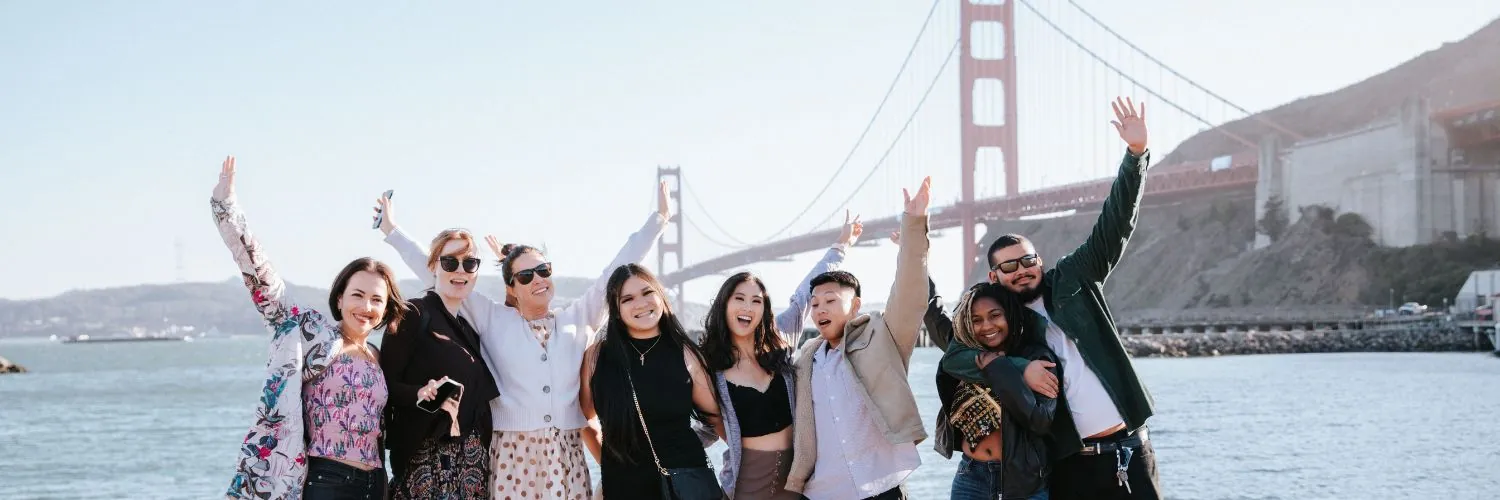 Group of friends posing by the Golden Gate Bridge on a sunny day.